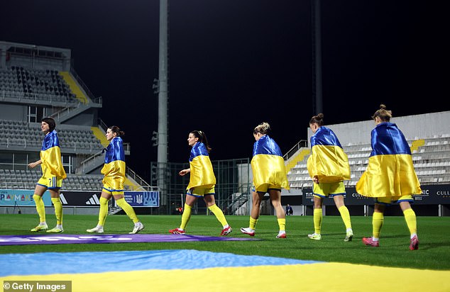 The Ukraine Women's Team Lined Up With Yellow And Blue Flags Draped Around Their Neck